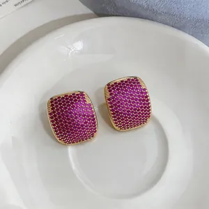 Macro view of elegant geometric earrings with magenta zircon pavé in a gold-tone setting