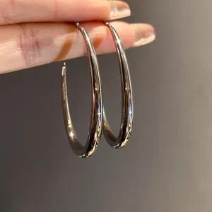 Primo piano dettagliato di orecchini a cerchio ovali in argento minimalisti con finitura lucida