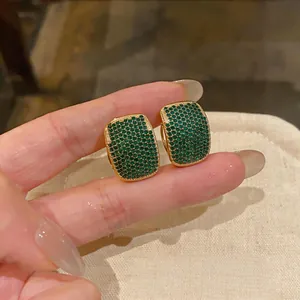 Detailed macro view of elegant gold stud earrings pavé-set with sparkling green zircons
