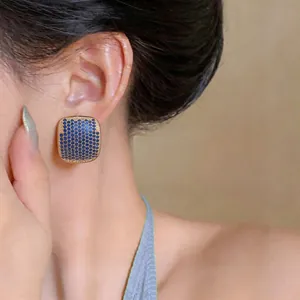 Close-up of elegant square earrings with blue micro-paved zircons on model's ear