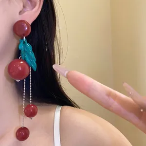 Elegant vintage red resin earrings with leaf detail and silver tassels on model ear