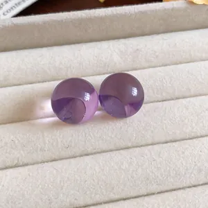 Vista macro de pendientes redondos de resina morada en una bandeja de terciopelo beige