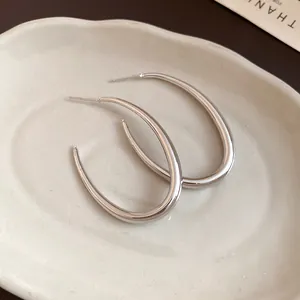 Vista dettagliata di orecchini a cerchio ovali in argento su un piatto ceramico