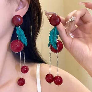 Detailed view of vintage cherry-style earrings with red resin beads and green leaf tassels