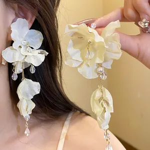 Vista dettagliata di eleganti orecchini a fiore in chiffon bianco con perle e cristalli