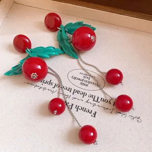 Detailed macro view of vintage red resin cherry earrings with green leaves and silver chain tassels