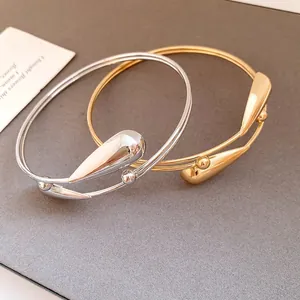 Close-up detail view of double-layer metal bangles with polished water drop accents