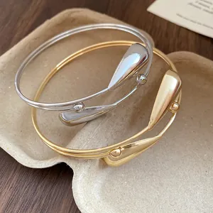 Macro view of vintage style double-layer open bangles with teardrop accents in gold and silver.