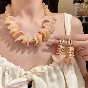 Detail van retro perzik acryl kralenketting en schelpvormige bloemblaadjes oorbellen