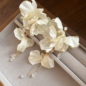 Dettagliata vista ravvicinata di eleganti orecchini a fiore in chiffon crema con perle