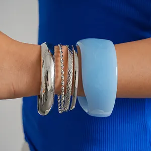 Set of five geometric metallic and light blue resin bangles displayed on a female wrist