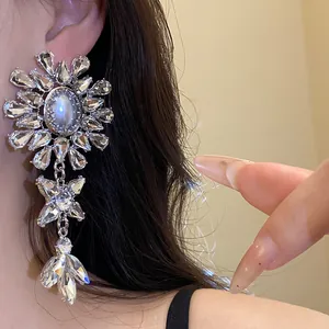 Close-up of a luxurious rhinestone and pearl floral dangling drop earring on model