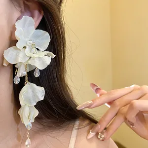 Dettaglio macro dell'elegante orecchino a fiore in chiffon bianco con perle e cristalli