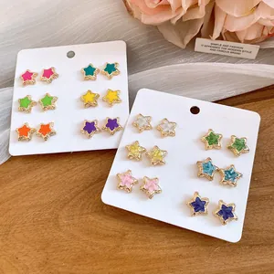 Close-up of colorful star-shaped enamel stud earrings set on white display cards.