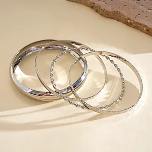 Detailed view of silver minimalist 5-piece bangle set with twisted and smooth textures.