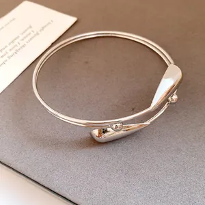 Close-up macro view of elegant silver double-layer open bangle with teardrop ends