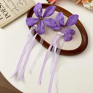 Close-up detail of elegant purple fabric flower hair clips with lace and ribbon tassels