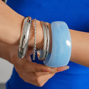 Close-up view of five-piece geometric metal and light blue resin bangles set on wrist.