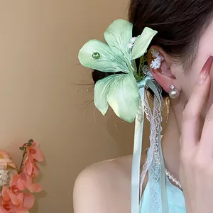 Close-up detail of a green fabric flower hair clip featuring elegant lace ribbons and bow
