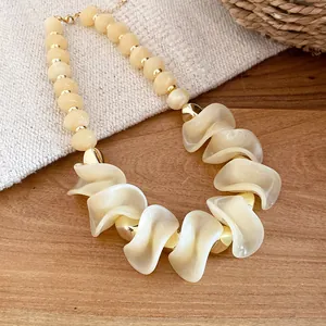 Detailopname van retro acrylaat ketting met onregelmatige crème kralen en gouden accenten