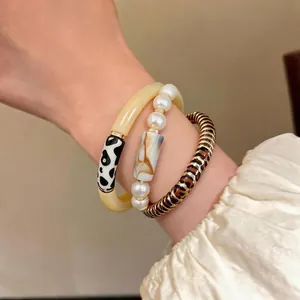 Vintage acrylic leopard and cow print stacked bracelet set with elegant pearls on wrist