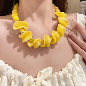Close-up van gele acryl ketting met onregelmatige gegolfde kralen en gouden accenten
