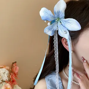 Detailed view of a blue fabric flower hair clip with elegant lace ribbons and pearls.