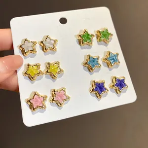 Close-up detail of 6 pairs of vibrant colorful star stud earrings on a white display card