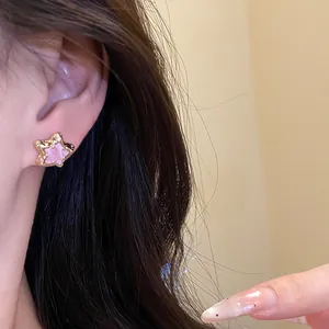 Close-up view of a sweet pink star-shaped oil-drop stud earring on ear