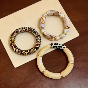 Close-up view of three vintage acrylic bracelets featuring leopard, marbled, and pearl designs.