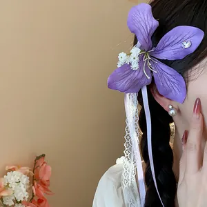 Detail view of a purple fabric flower hair clip with delicate white lace ribbons