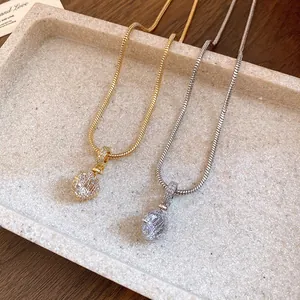 Detail view of gold and silver snake chain necklaces with sparkling round zircon pendants.