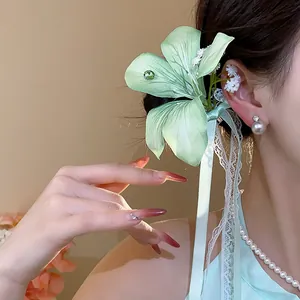 Close-up of light green fabric flower hair clip with delicate lace ribbons on model