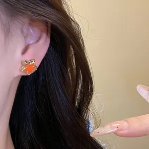 Detailed macro view of a sweet star-shaped stud earring with orange enamel dripping oil finish