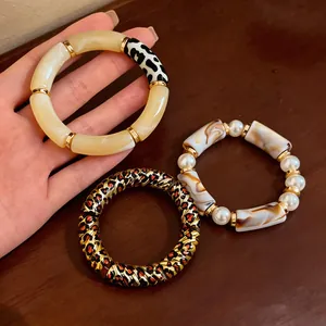 Detailed view of leopard print acrylic and pearl beaded bracelets with gold accents
