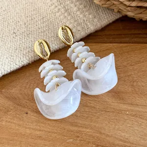 Detailopname van retro oorbellen met onregelmatige acryl kralen en gouden schelp.