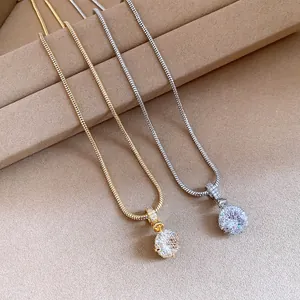 Close-up of gold and silver zircon pendant necklaces with elegant snake chains on a warm background
