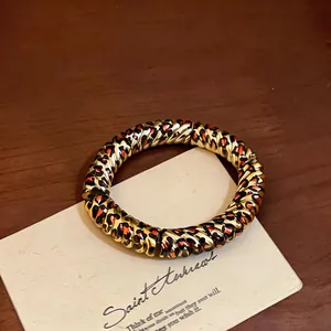 Close-up of a retro acrylic bracelet with a gold twisted texture and leopard print spots.