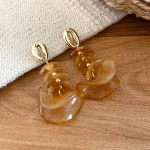 Gedetailleerd overzicht van amberkleurige acryl oorbellen met elegante gouden schelpstud