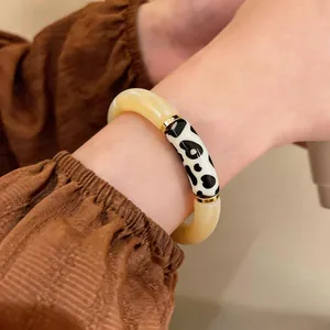 Close-up view of a vintage acrylic bracelet with cow print splice detail on a model's wrist