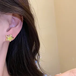 Close-up detail shot of a gold star stud earring with yellow enamel worn on ear