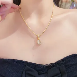 Detailed view of an elegant gold zircon ball pendant necklace on a model's neck