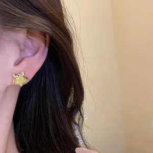 Detailed macro shot of a sweet yellow enamel star stud earring on a model's ear