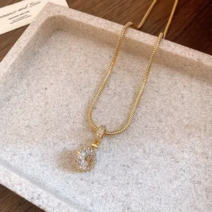 Detailed macro shot of a golden snake chain necklace with a zircon-paved round pendant