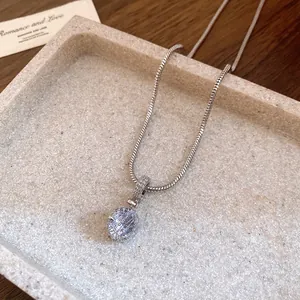 Macro view of an elegant round zirconia pendant necklace placed in a stone tray.