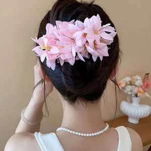 Elegant pink fabric flower hair clip shown on model's bun hairstyle for vacation style