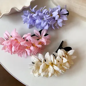 Close-up of three floral fabric hair clips in purple, pink, and white with water drops