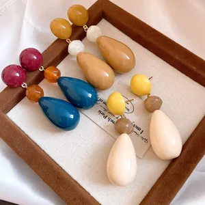Macro view of multiple pairs of vintage resin waterdrop dangle earrings in varied rich colors.