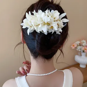 Detailed back view of a white fabric flower hair clip worn in an elegant bun.