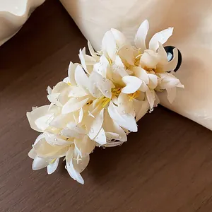 Close-up detail of an elegant white fabric flower hair clip decorated with clear beads